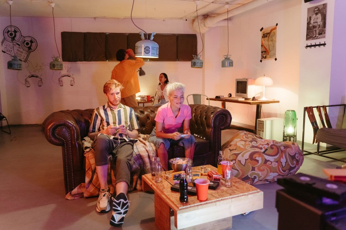 Friends sitting together on a sofa playing a video game with retro controllers