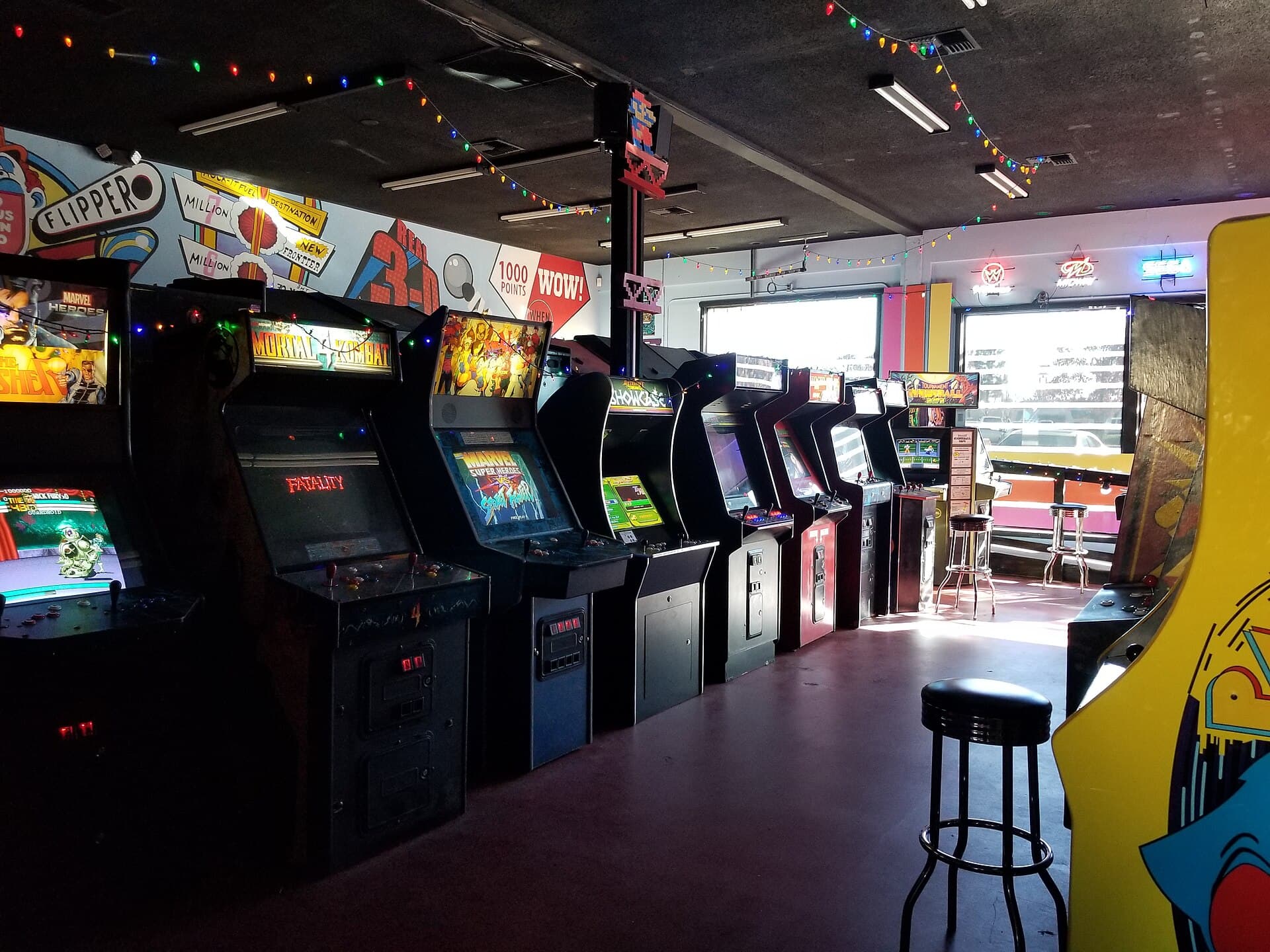 Rows of illuminated retro arcade cabinets in a dim arcade